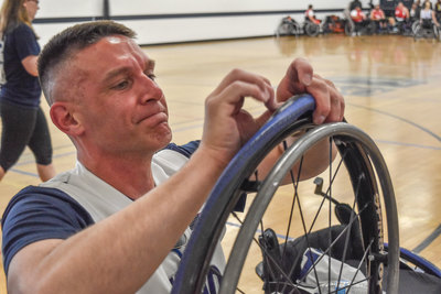 Rick White is repairing the tire of a wheelchair.